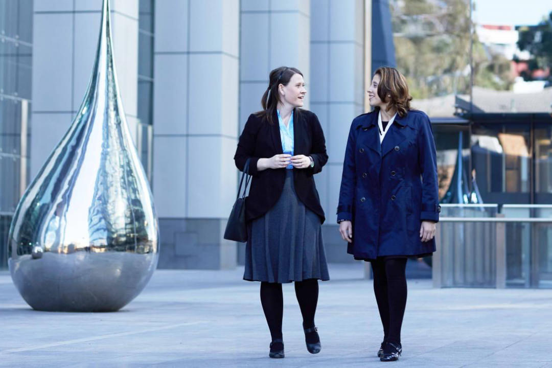Two female solicitors engaged in conversation outside the law courts building.