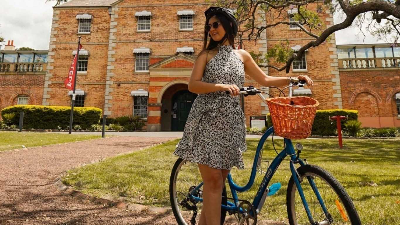 woman standing next to a bike in front of the female orphan school parramatta