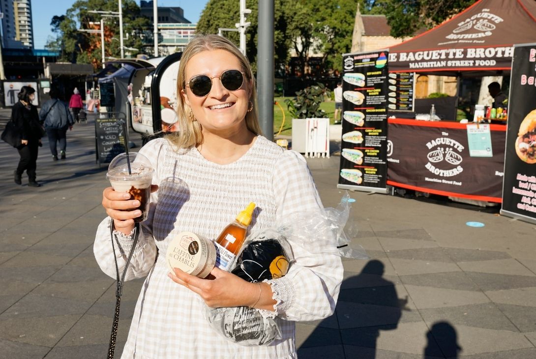 woman standing at the farmers markets holding fresh produce in her arms