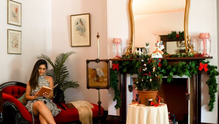 woman sitting on a sofa inside Hambledon Cottage reading a book