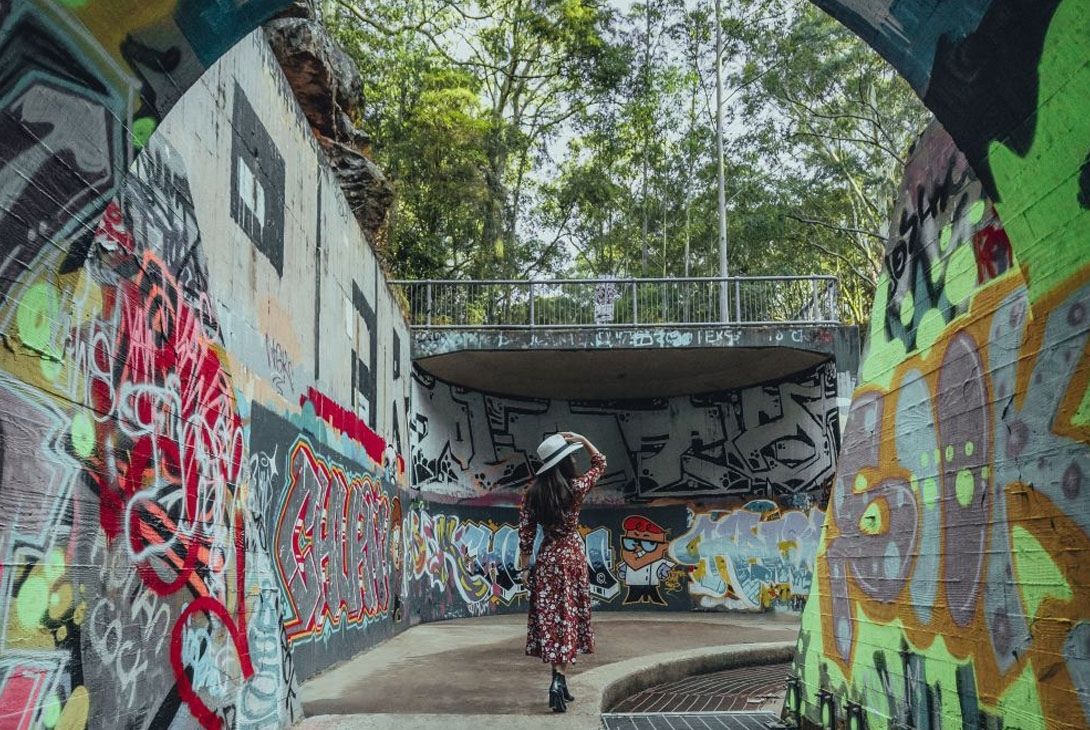 woman walking through graffiti tunnel