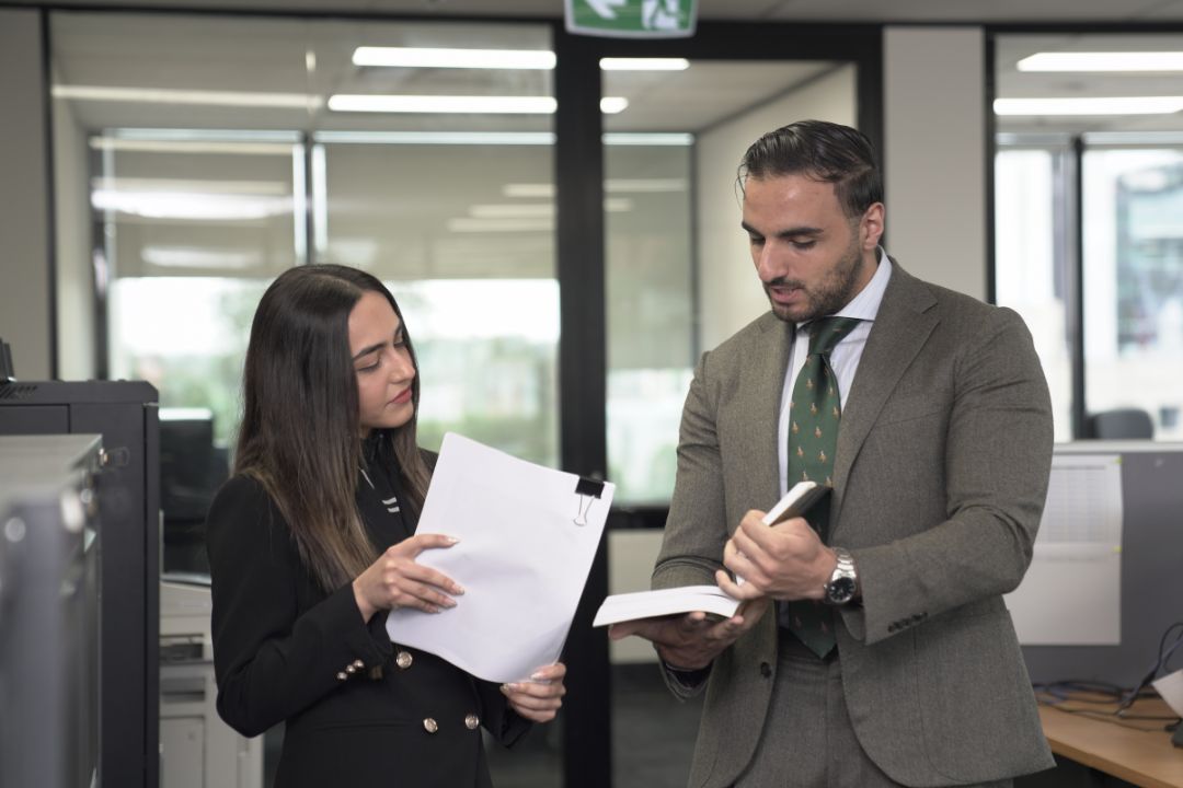 Two people in corporate wear looking at paperwork
