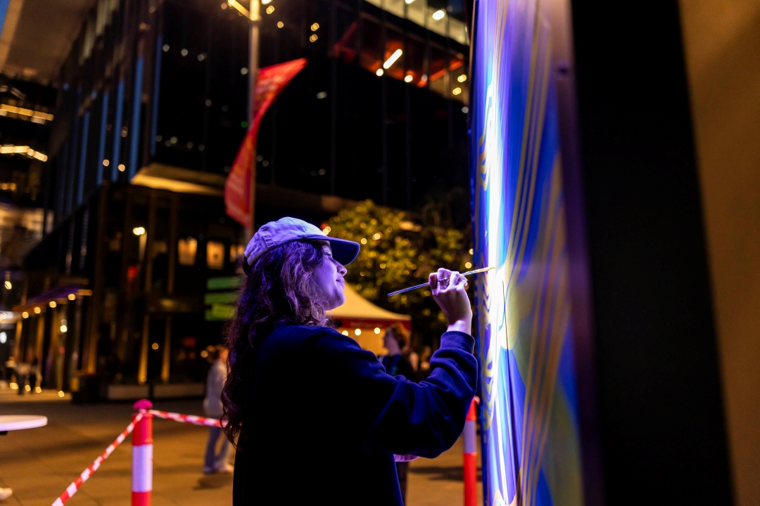 Woman with paintbrush in front of artwork