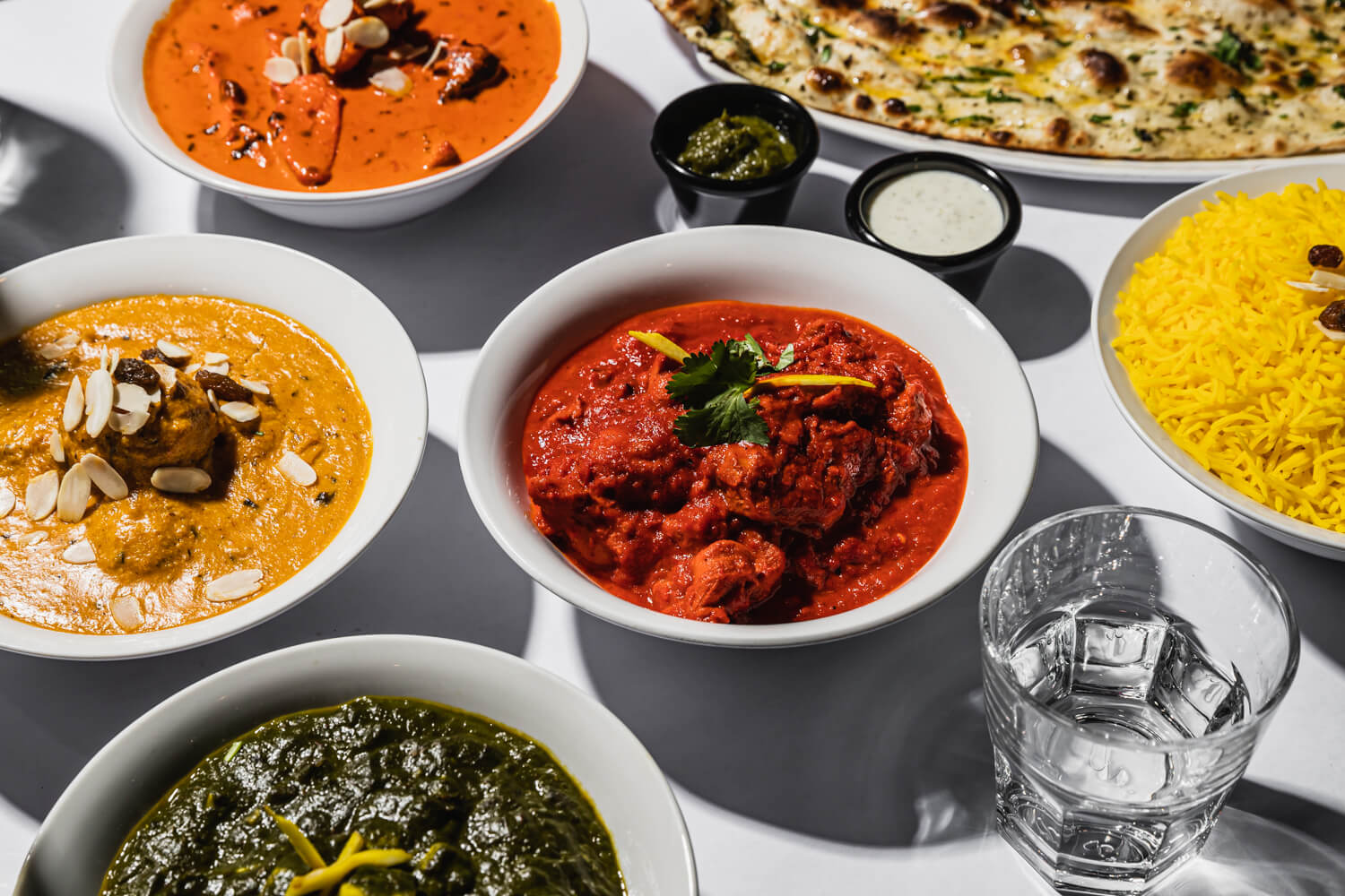 table of bowls full of brightly colour Indian food 