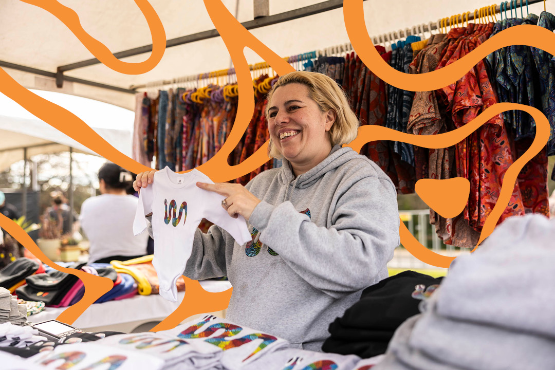 Smiling women handing over clothing at market stall