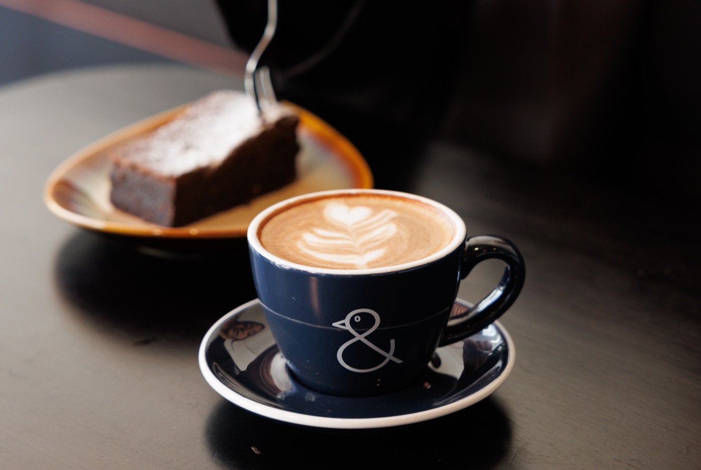 A person sitting at a coffee table, featuring two freshly prepared cups of coffee.