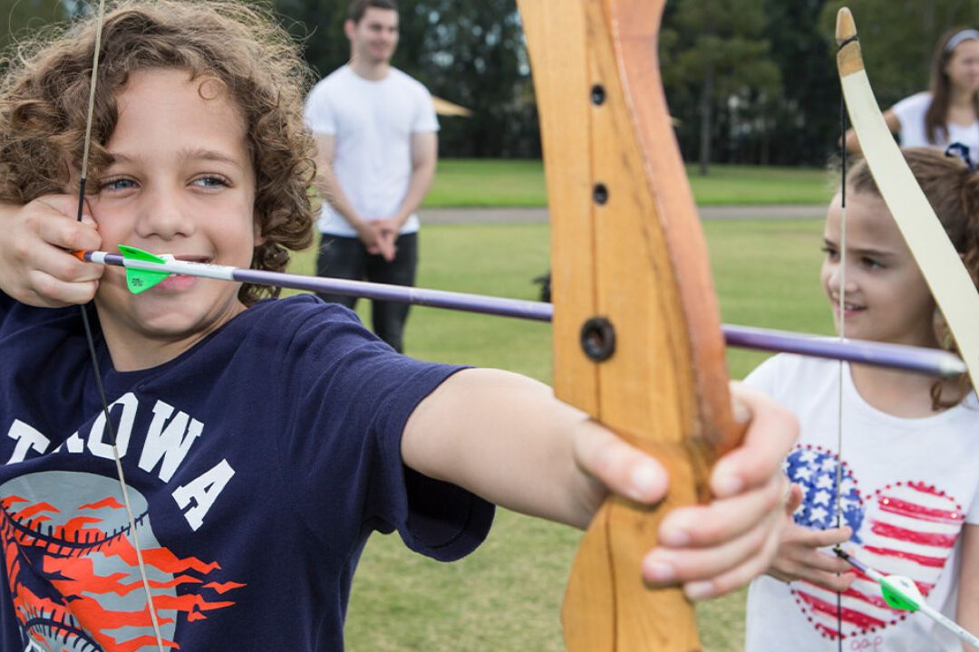Boy with curly hair holden a wooden archery bow