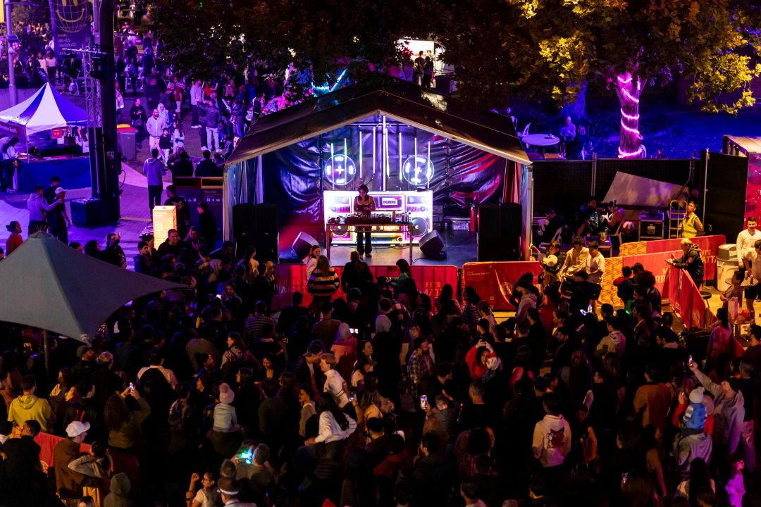 Large crowd looking at musician on stage at night surrounded by purple lights