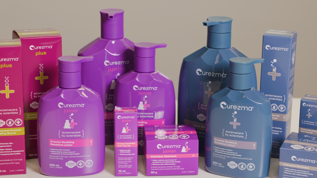 Various vibrant hair care products, including bottles and boxes, are arranged on a surface. The packaging is in shades of pink, purple, and blue.