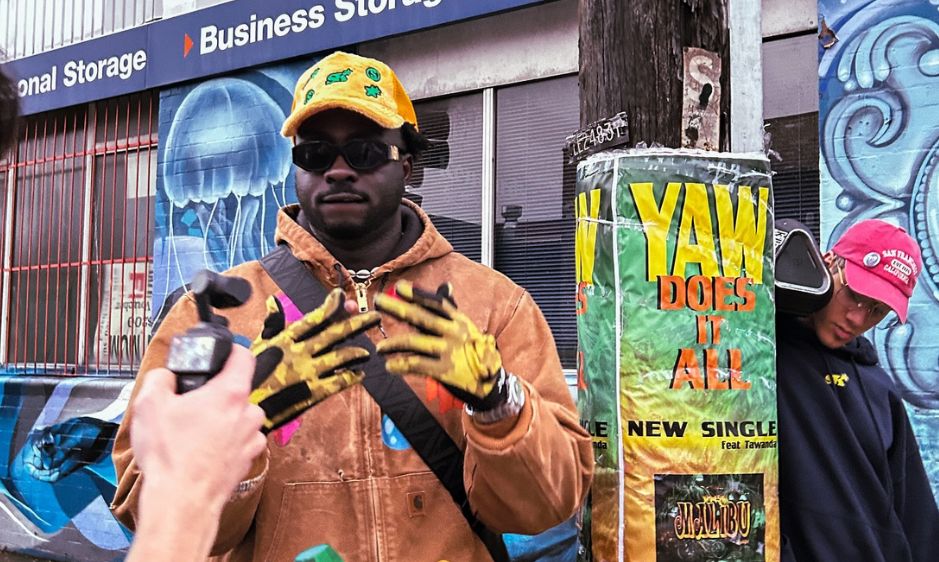 Man standing in front of a poster and graffiti wall