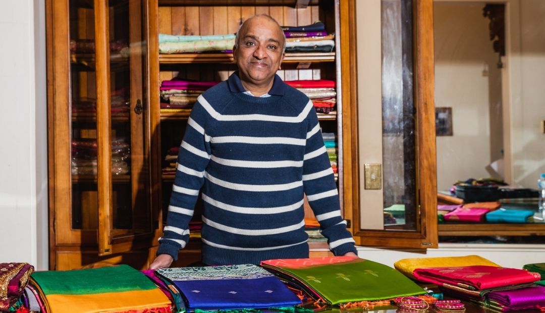 Man smiling selling sari material