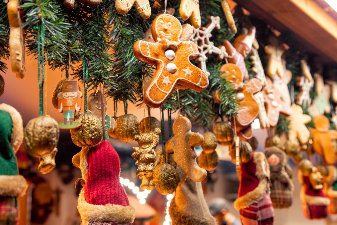 Festive Christmas market stall with hanging gingerbread cookies, including reindeer and stars, surrounded by warm lights and holiday decorations.
