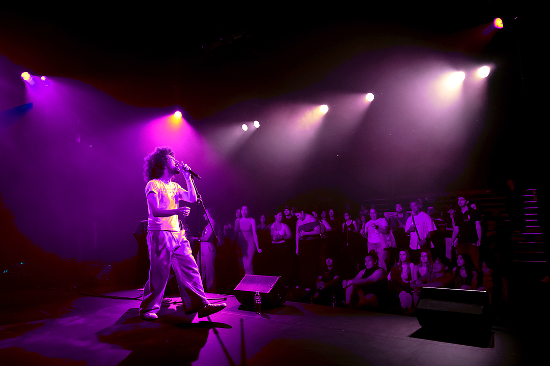 Man on stage singing in front of a crowd