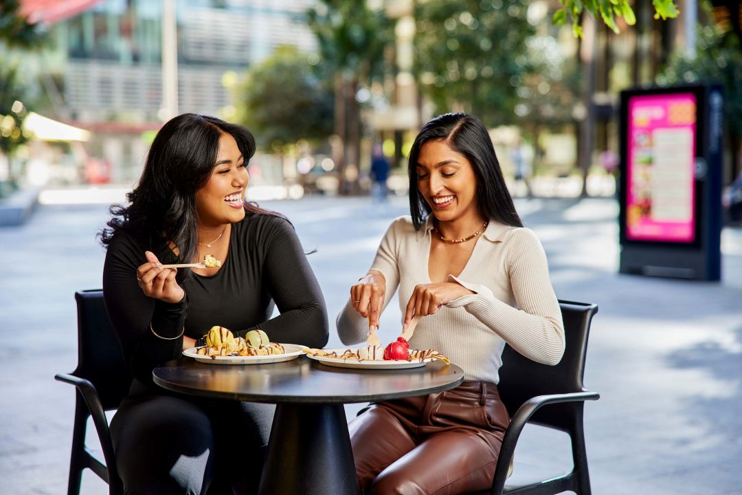 Two girls sitting, eating food