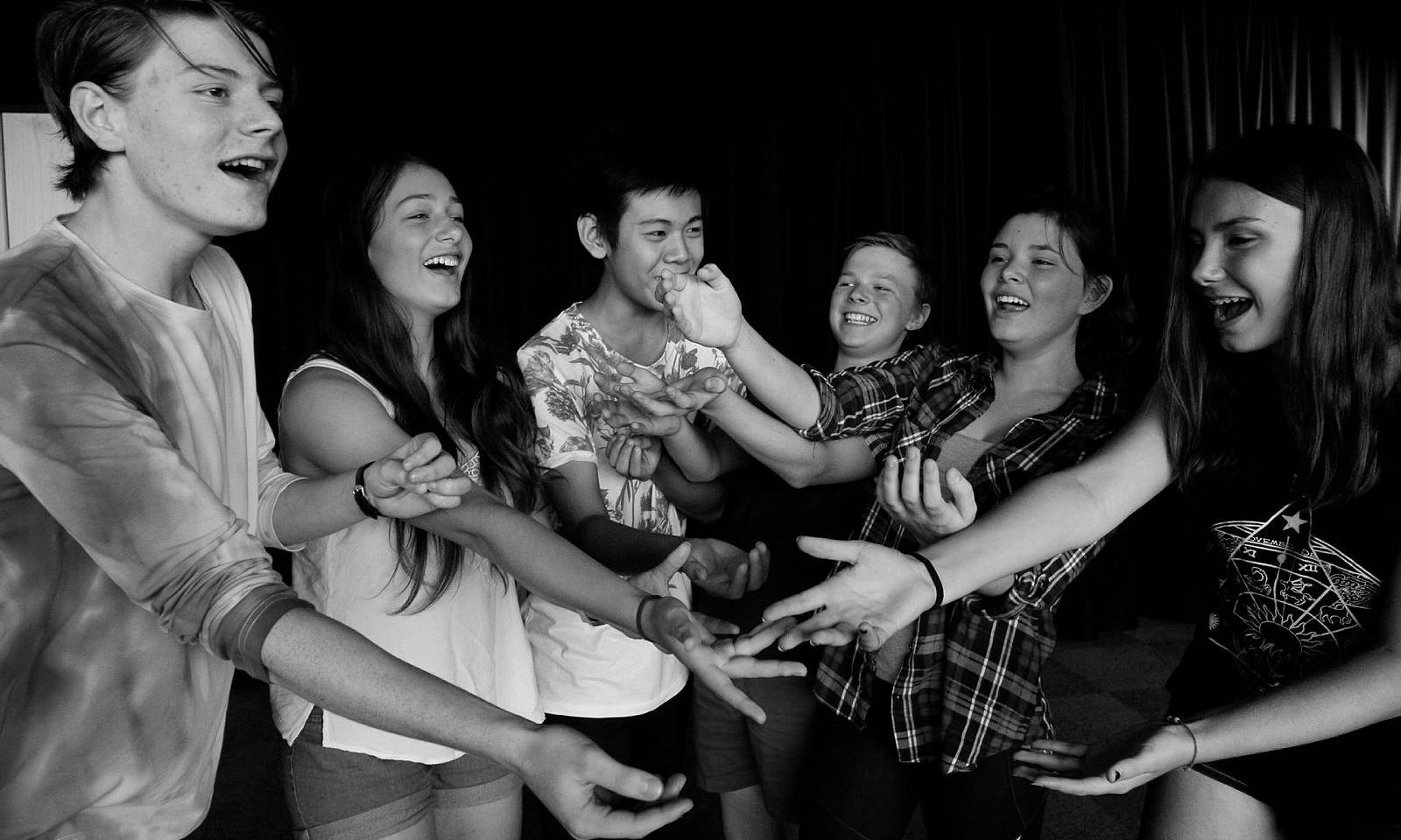 Teenagers with their hands outstretched and doing a performance together