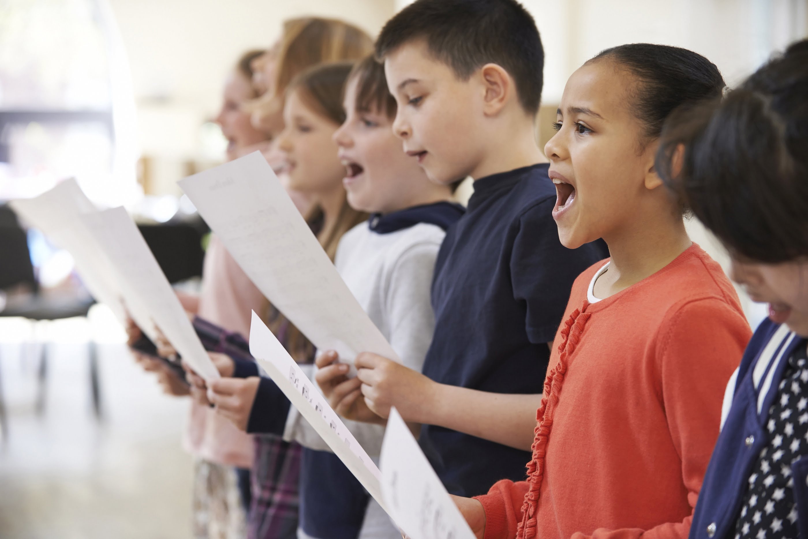 Kids singing together and holding a sheet of paper