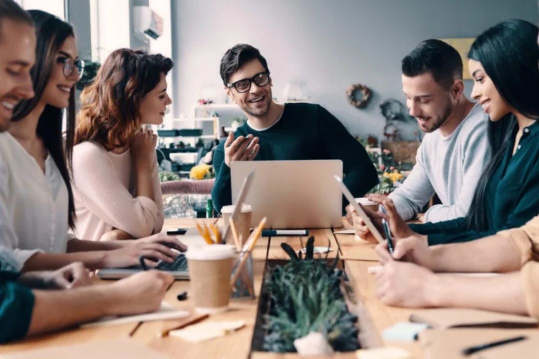 A group of men and women sitting around desk, on computers