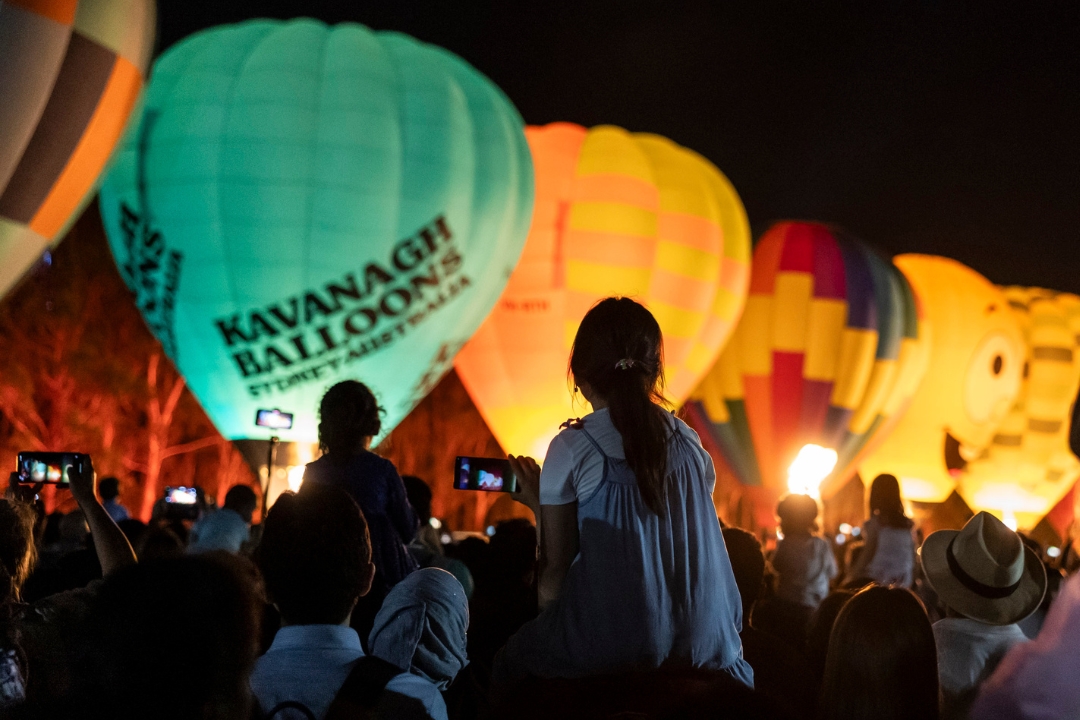 Silhouette of people looking at lit uphot air balloons