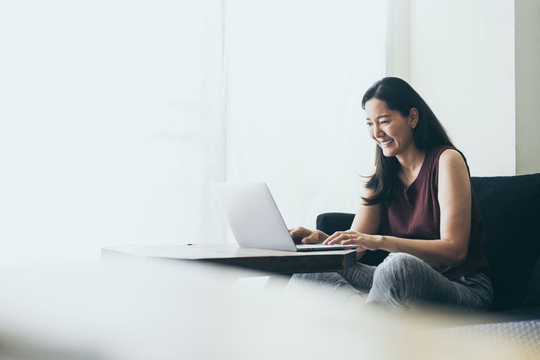 Women sitting on couch smiling at computer