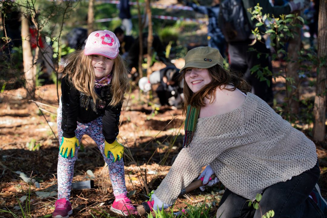 Little girl and lady wearing hats planting trees