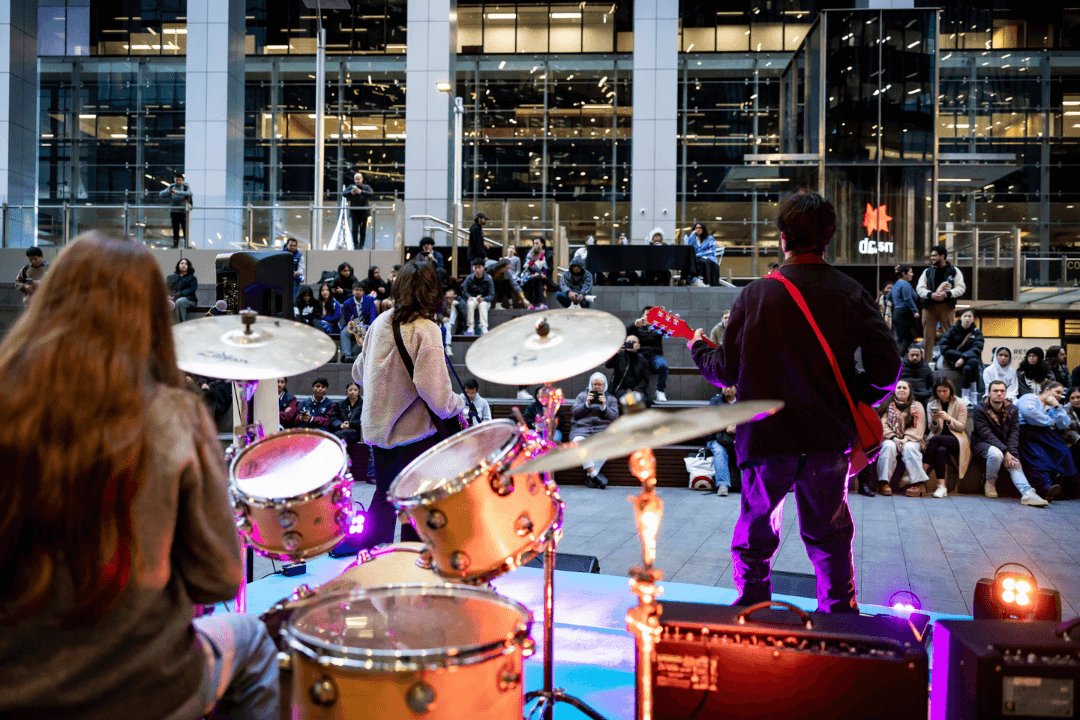 View of Parramatta Square from behind drumkit with two guitarists