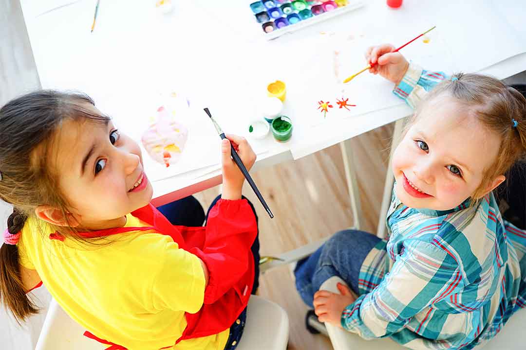 Young children looking up while painting