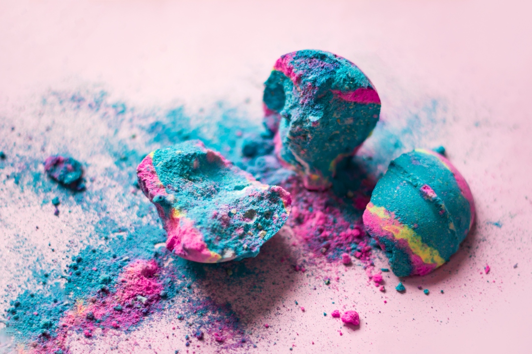 Broken colourful bath bombs on pink background