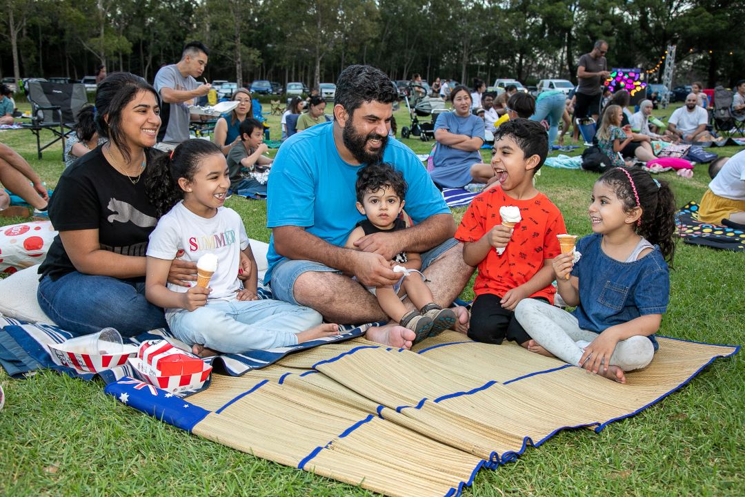 Family sitting on a rug in the park