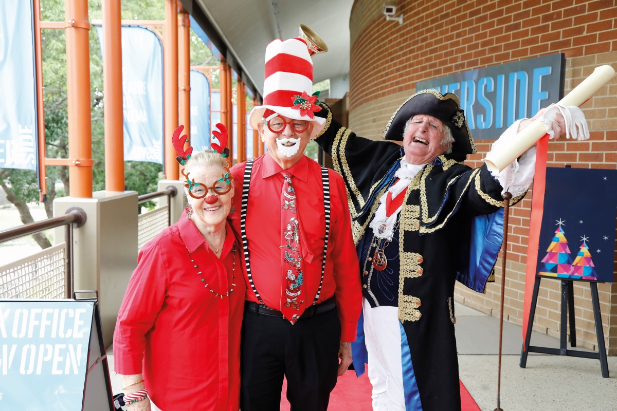 Elderly couple wearing christmas decorations with town crier