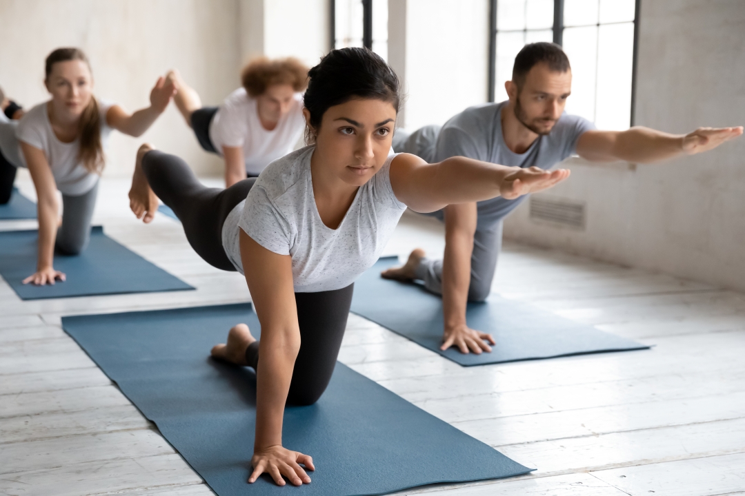 2 women and 2 men stretching on yoga mats