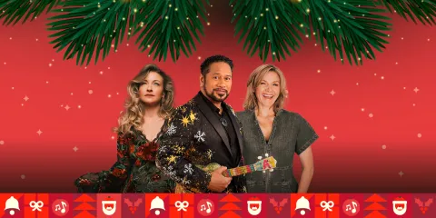 Three actors pose before a festive red backdrop, one holding a decorated guitar beneath evergreen branches; holiday icons line the bottom, creating a cheerful seasonal mood.