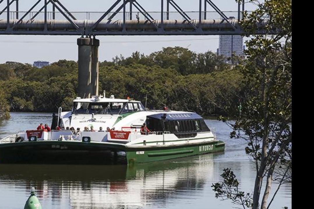 Image of a Sydney Ferries River-Cat passenger catamaran making its way upriver to Sydney with the Parramatta Skyline in the background. 