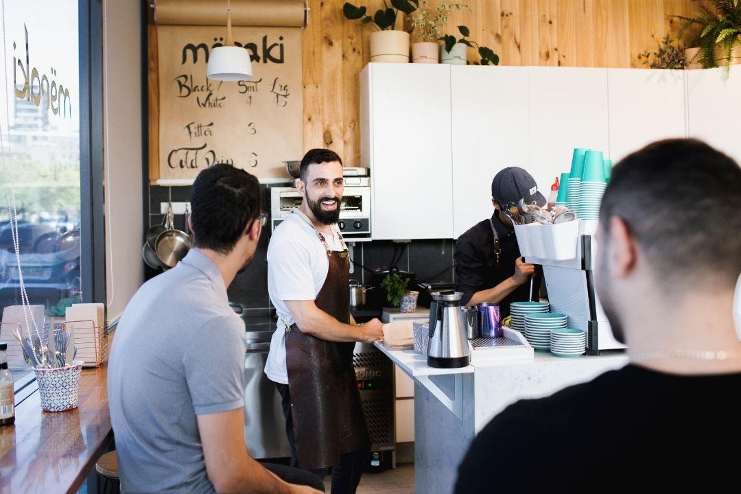 1 man serving coffee to other men in Meraki merchants cafe