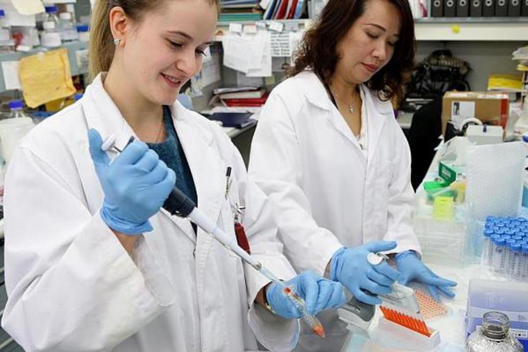 A medical student works alongside a senior doctor in the lab performing analysis on test tube samples.