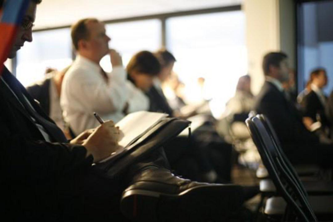 Small business entrepreneurs listen intently and take notes during a seminar on small business social media practices 