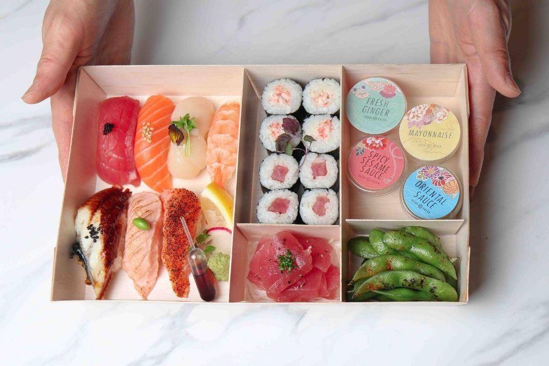 Hands holding sushi bento box