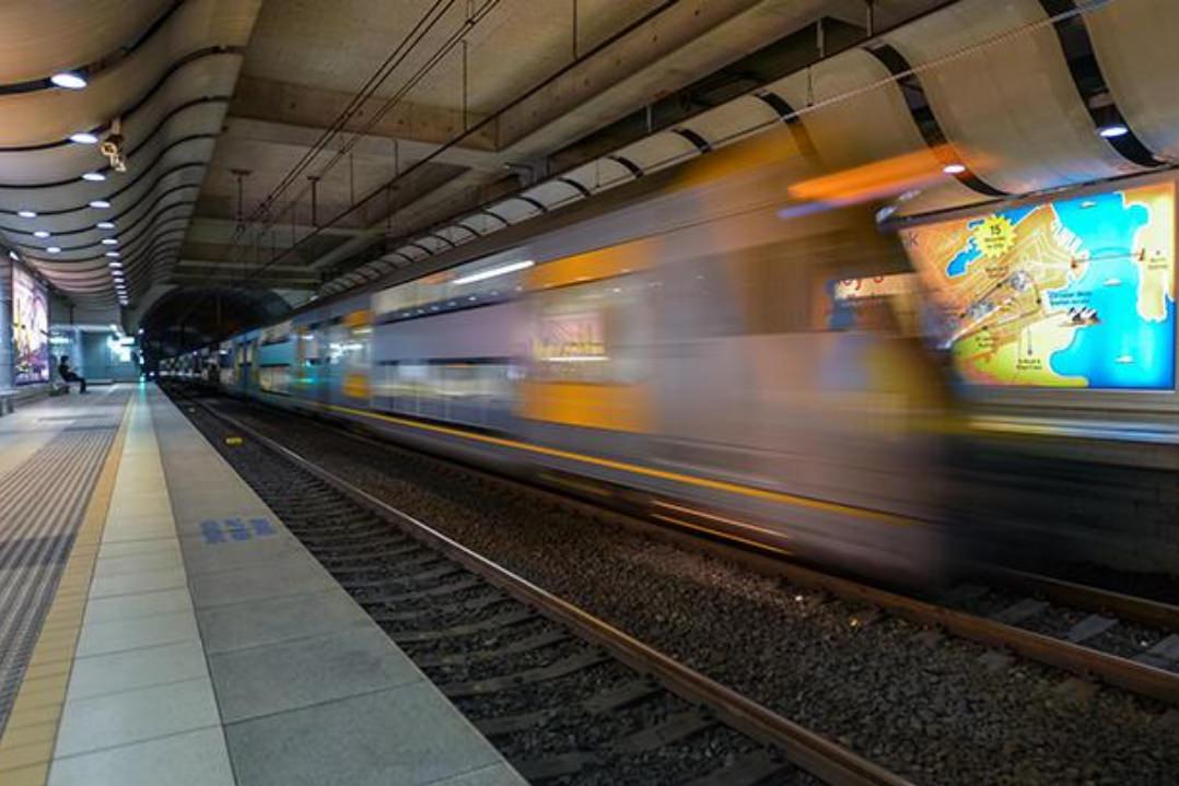 Image of a NSW State Transport train speeding through the airport terminal. The train has had a blurred effect applied to create the illusion of speed.