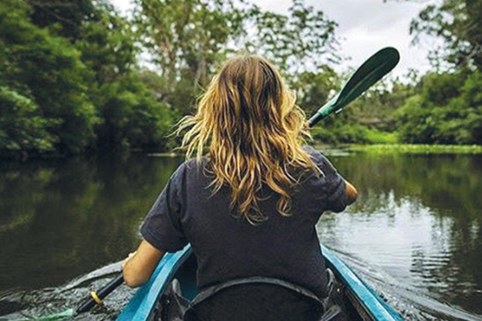 Image of a woman kayaking in a peaceful reflective arm of Lake Parramatta 
