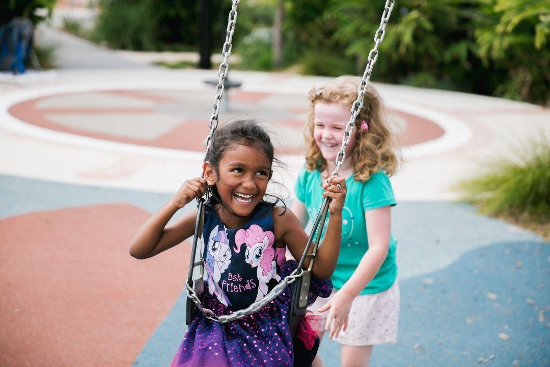 Kids pushing each other on swings