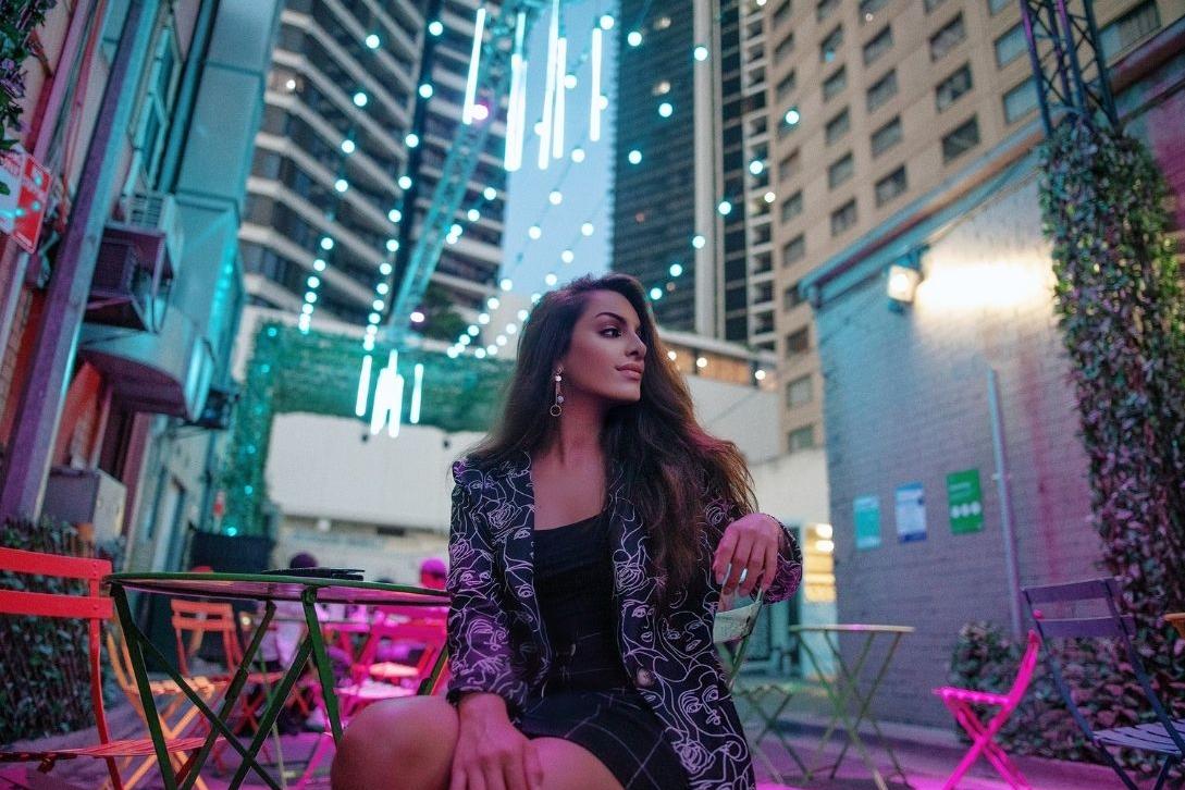 woman in phillip lane outdoor dining area at nighttime with office buildings behind her