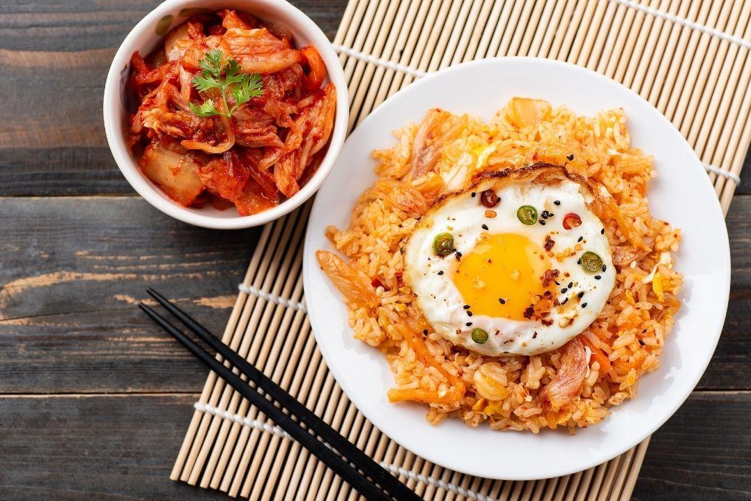 kimchi in one bowl and egg fried rice on a plate with chopsticks