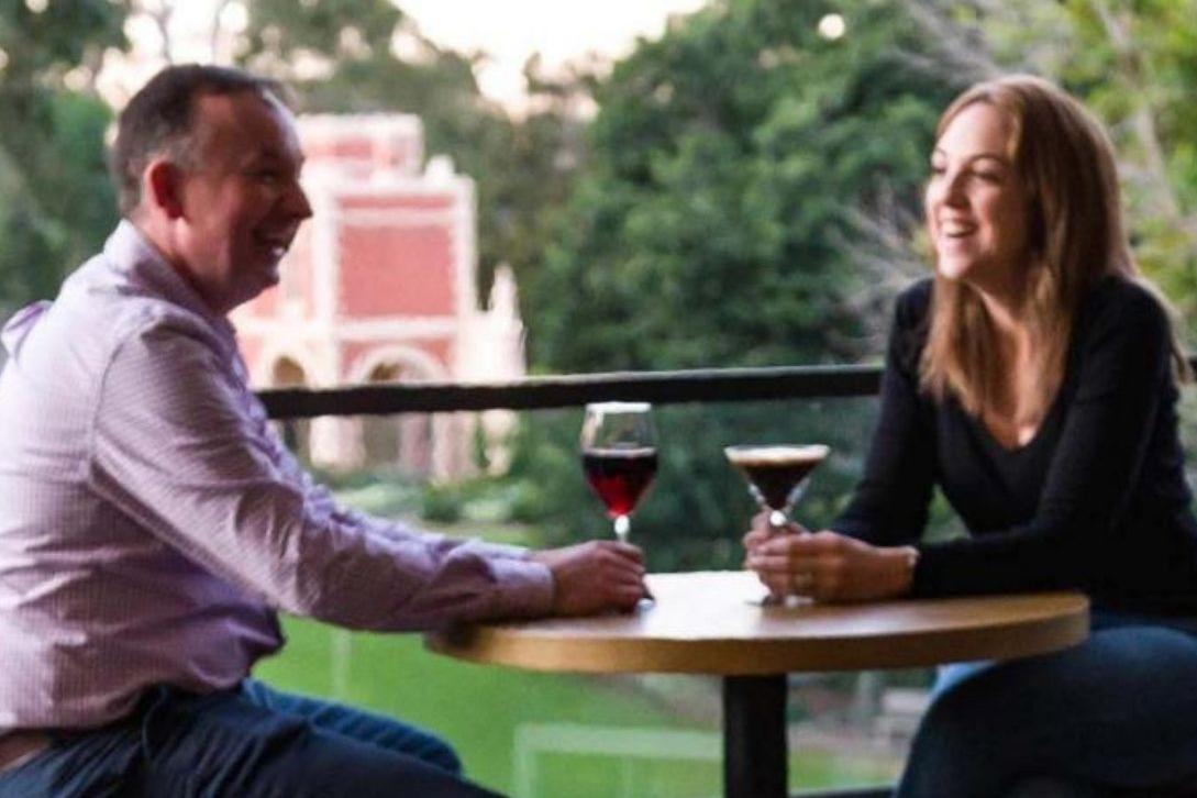 man and woman sat at a table having some alcoholic beverages