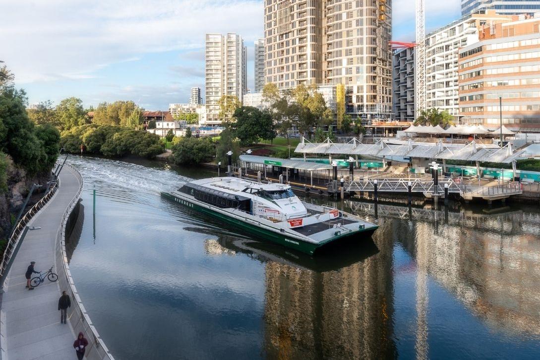 parramatta ferry coming into the wharf. cyclist on the escarpment boardwalk nearby