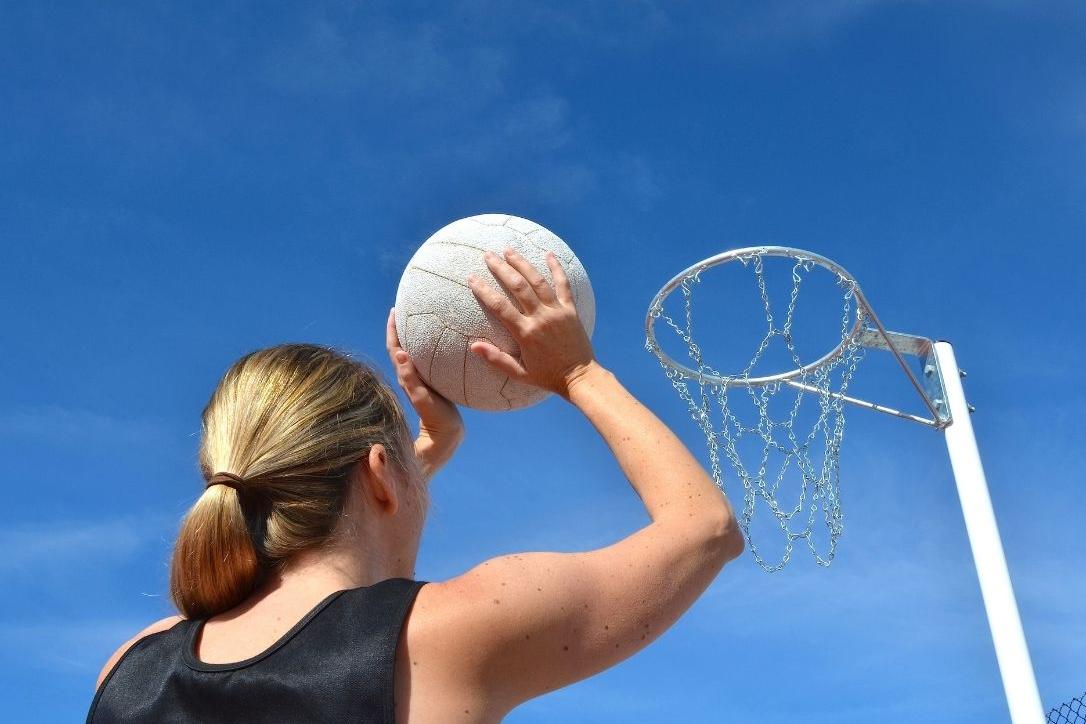 woman aiming netball into hoop