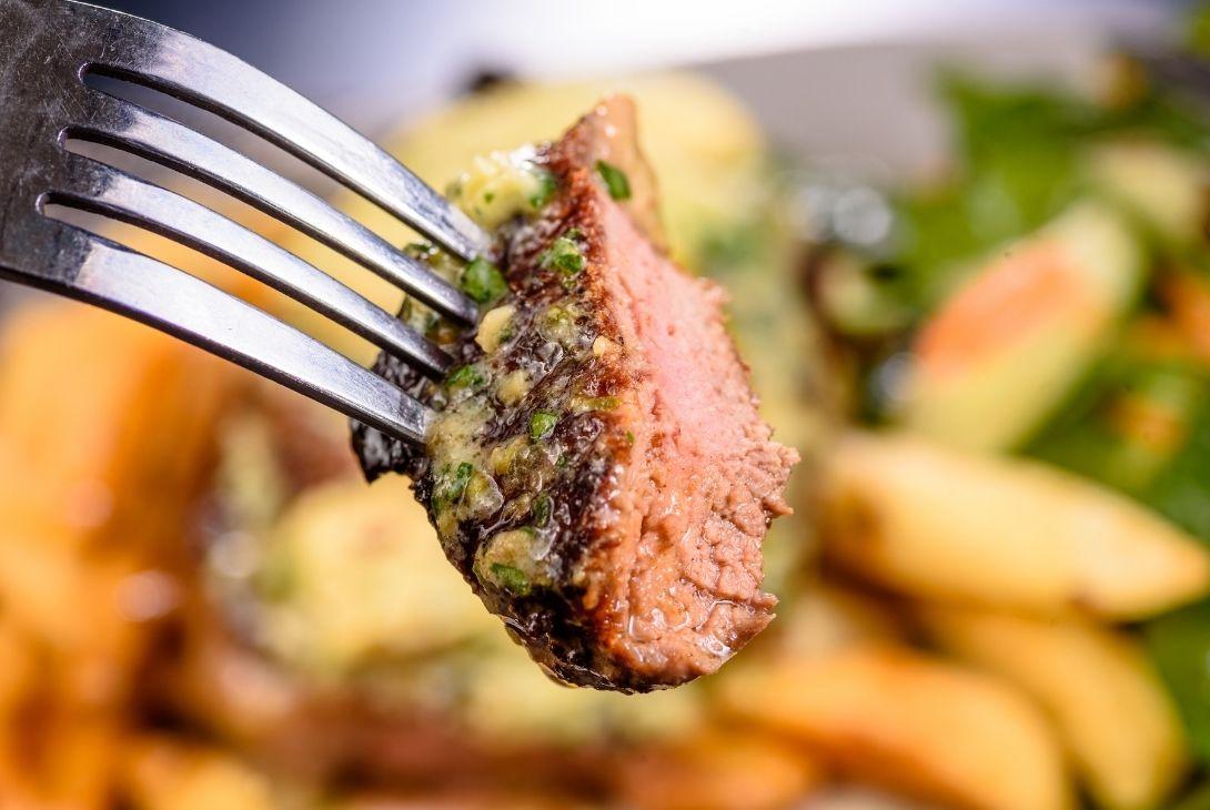 steak on a fork with chips in the background