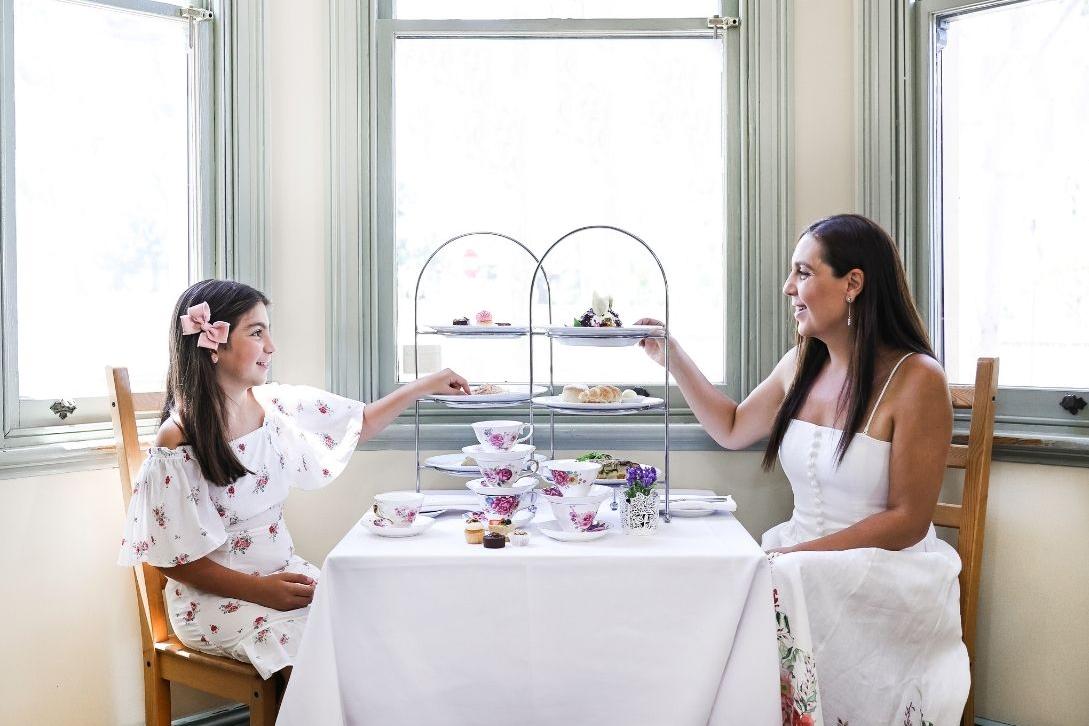 mother and daughter sat at a table enjoying a high tea