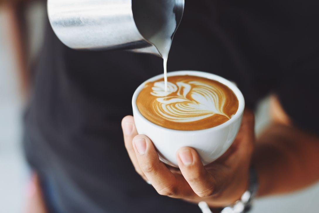 barrista pouring milk into coffee cup