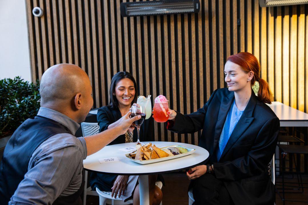 office workers cheersing cocktails around a bar table