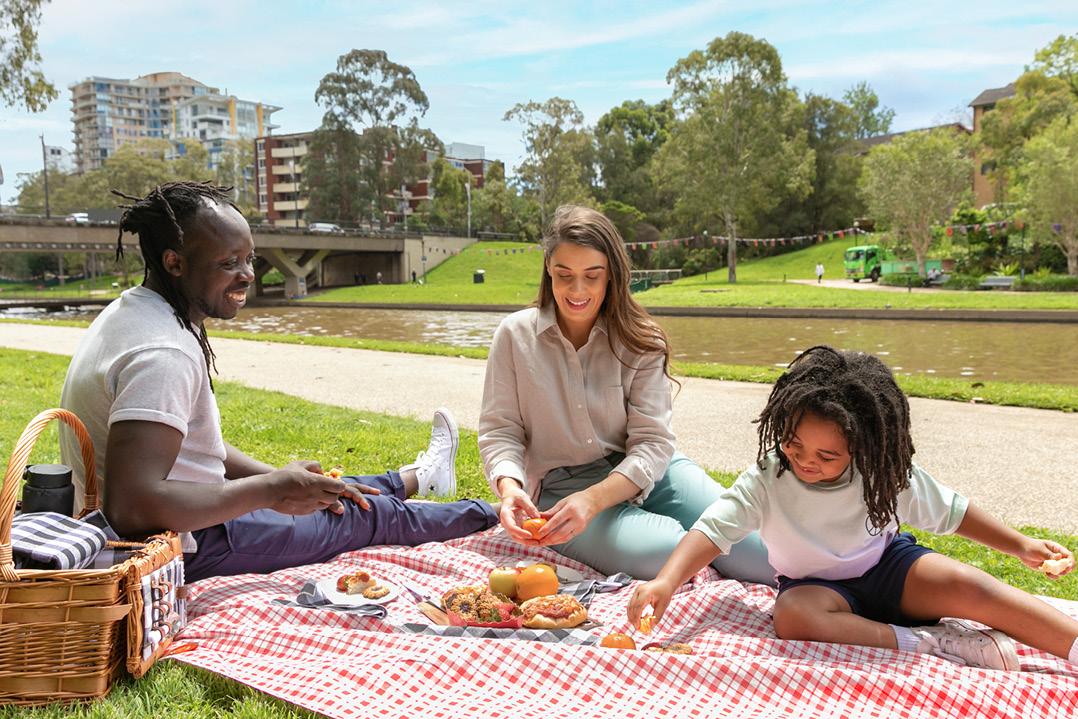 Three people picnicing on the banks of the Parramatta River. 