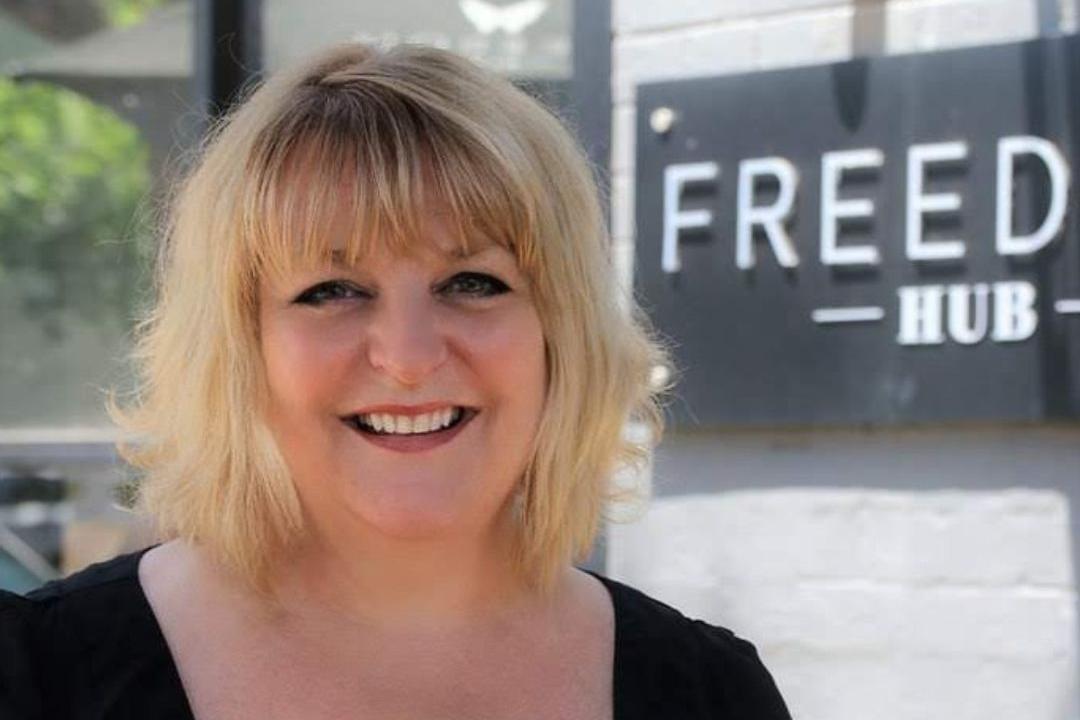 Woman standing in front of a sign that says 'Freedom Hub'